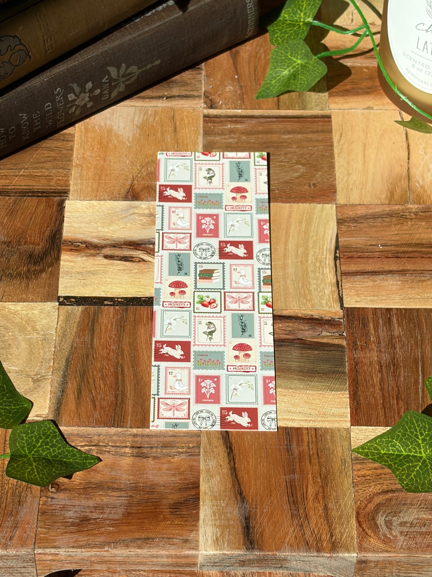 A bookmark with a variety of red, green, and cream stamp designs arranged in a pattern. The bookmark is sitting on a wooden background. 